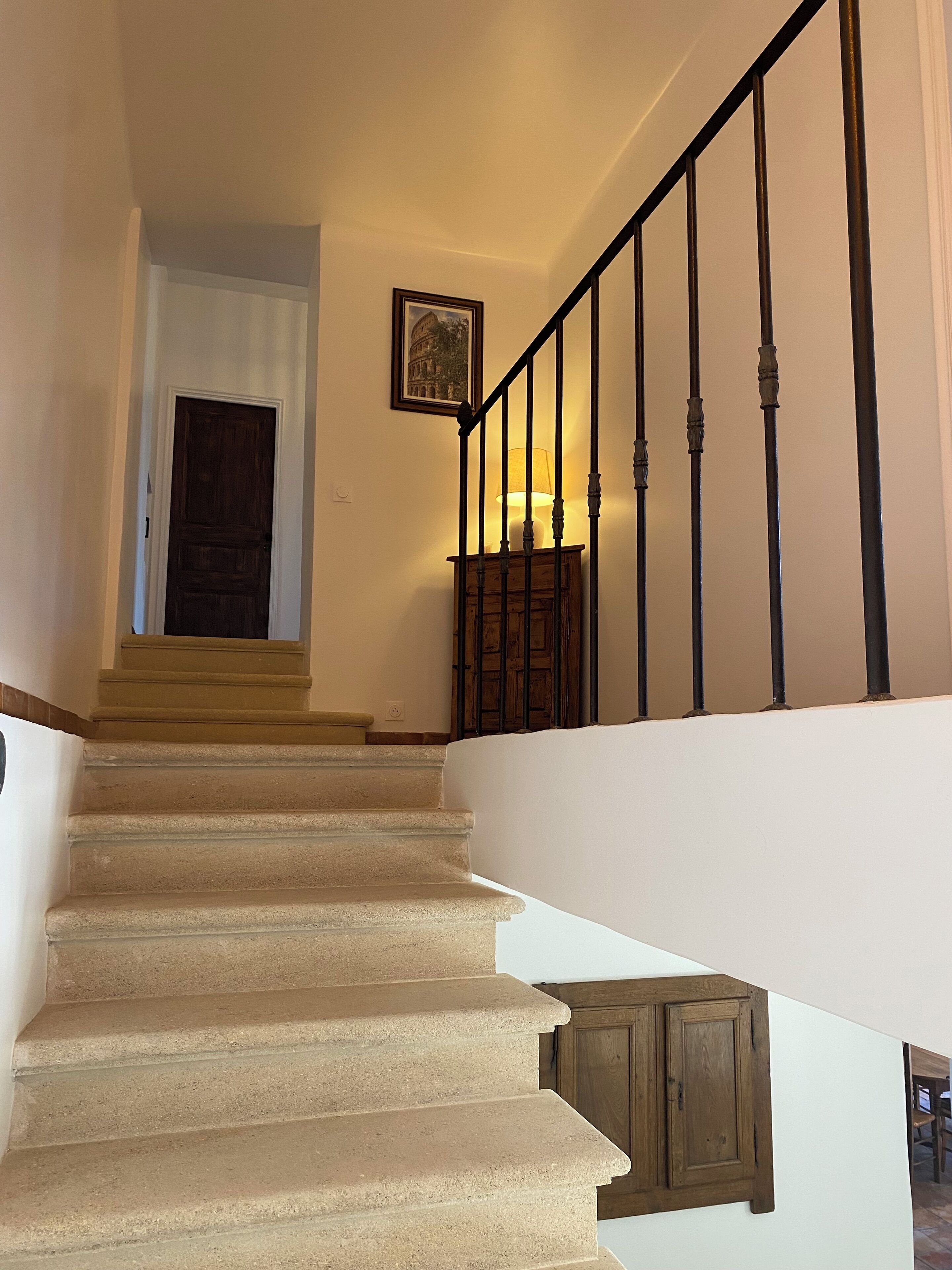 Eine Treppe mit hölzernem Geländer und einer Lampe auf der Podestfläche.