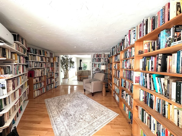 Une pièce spacieuse avec des étagères en bois remplies de livres, une grande moquette et un canapé.