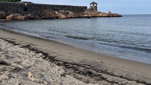 A coastal scene with a stone pier leading to a small gazebo, a sandy beach, and a house in the background. - Newly Updated! Private Pool! Walk to Beach, Shops, Restaurants & Train to Salem! (Rockport)