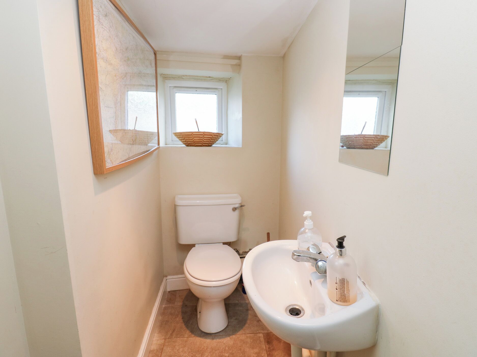 A small bathroom with a toilet, sink, and a mirror.