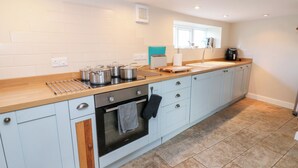 A modern kitchen with white cabinets, a wooden countertop, and a built-in oven. - Rosemary Cottage (Leyburn)