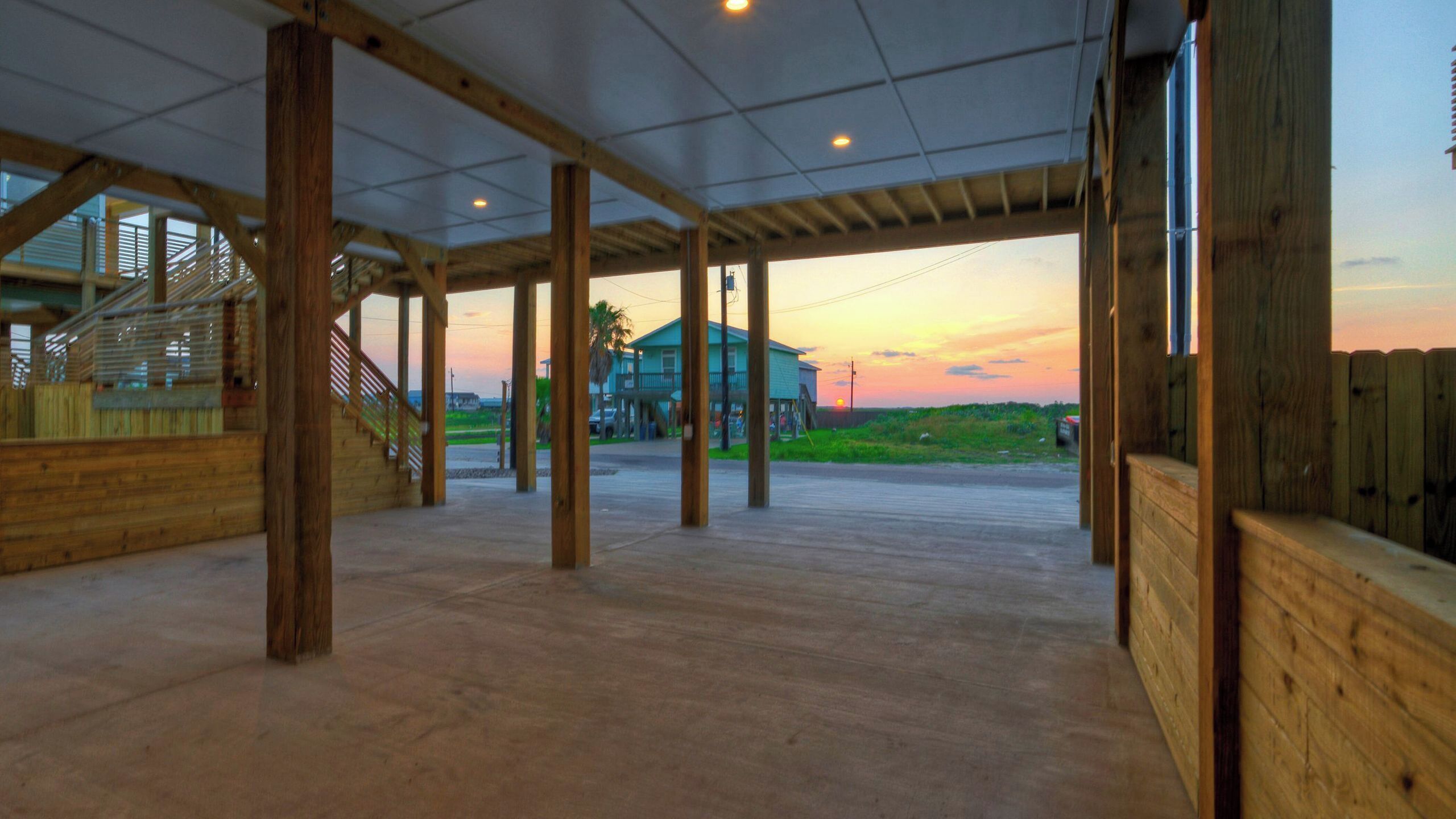Amplio espacio interior con vista a una casa y al atardecer.