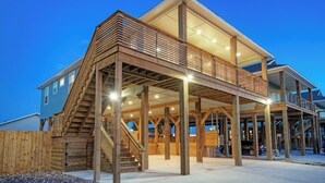 A multi-story building with a wooden deck and a staircase. - Pool, Firepit + Golf Cart Zone + Near Beach Looney Dunes by Avantstay (Port Aransas)