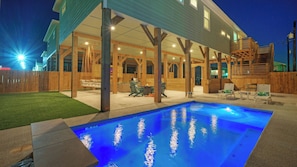 A pool with a blue light, wooden deck, and outdoor seating. - Pool, Firepit + Golf Cart Zone + Near Beach Looney Dunes by Avantstay (Port Aransas)