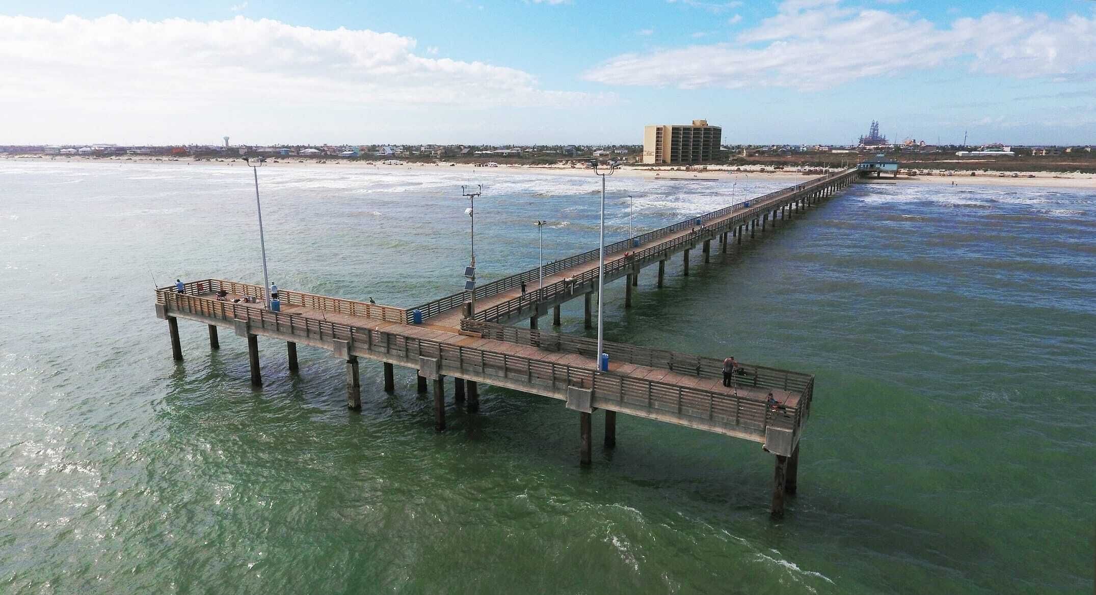 A pier extending into the water with a building in the background.
