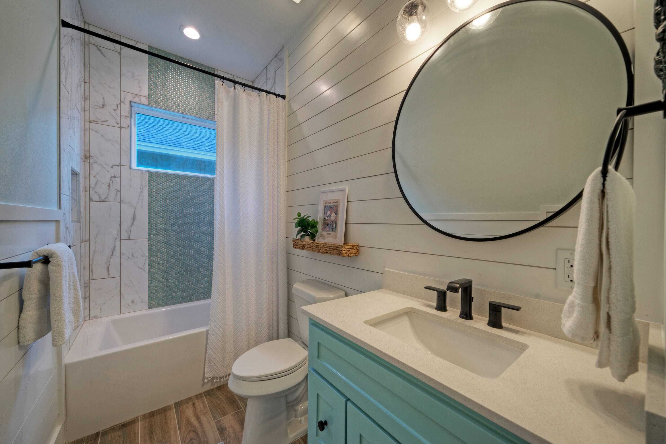 A bathroom with a bathtub, toilet, sink, and a large mirror.