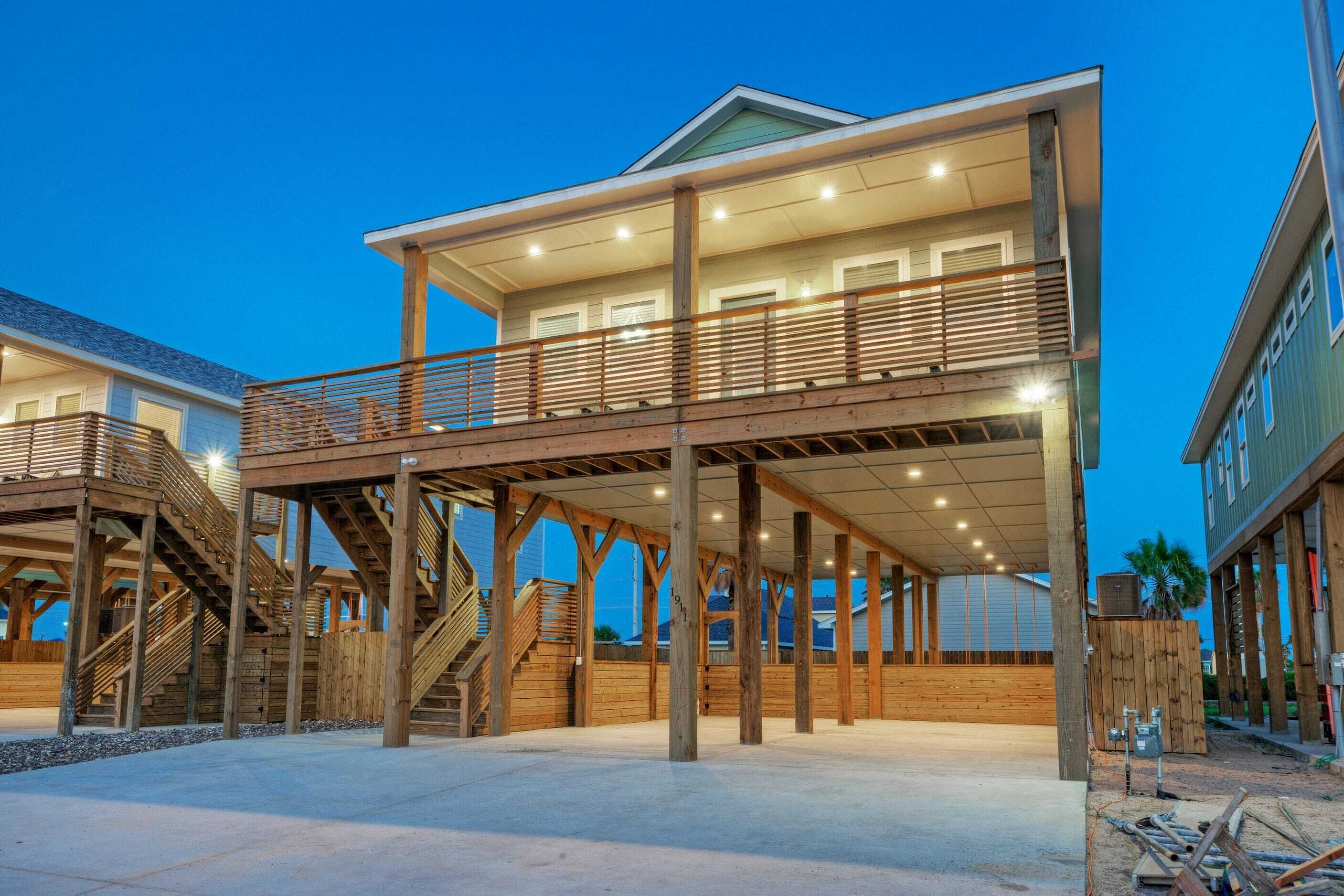 A multi-story house with a covered outdoor area, wooden deck, and a staircase leading to the upper level.