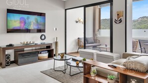 A modern living room with a flat-screen TV, a sofa, a coffee table, and a dining area. - Beautiful, cozy, upscale APT next to Las Ramblas (Santa Tecla)
