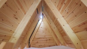 A triangular attic room with wooden walls and a sloped ceiling. - Robin (Woodbridge)