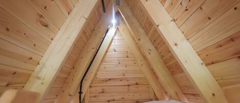 A triangular attic room with wooden walls and a sloped ceiling.