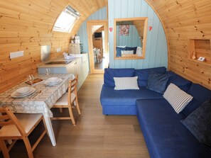 A cozy cabin interior with a dining area, a sofa, and a kitchen. - Bwthyn Bach Brefi (Tregaron)