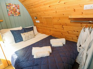 A cozy room with a bed, pillows, a quilted duvet, and a wooden wall. - Bwthyn Bach Brefi (Tregaron)