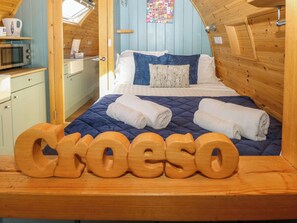 A cozy room with a bed, a wooden headboard, and a wooden sign spelling 'Croeso'. - Bwthyn Bach Brefi (Tregaron)