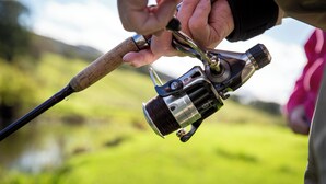 A close-up of a fishing rod with a reel, held by a person. - Bwthyn Bach Brefi (Tregaron)