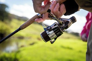 Et nærbillede af en fiskestang med en spole, holdt af en person.