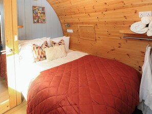 A bed with a red quilt, pillows, and a wooden headboard. - Ty Twt Teifi (Tregaron)