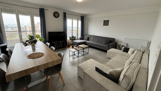A modern living room with a dining area, grey sofa, and a TV. - Modern Apartment for 9 in Loire (Le Mans)