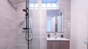 A modern bathroom with a glass-enclosed shower, a wooden vanity, and a large mirror. - Modern Apartment for 9 in Loire (Le Mans)