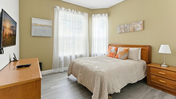 A bedroom with a bed, bedside table, lamp, and artwork on the walls.