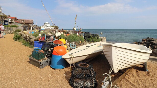 Una playa arenosa con equipo de pesca y un pequeño bote.