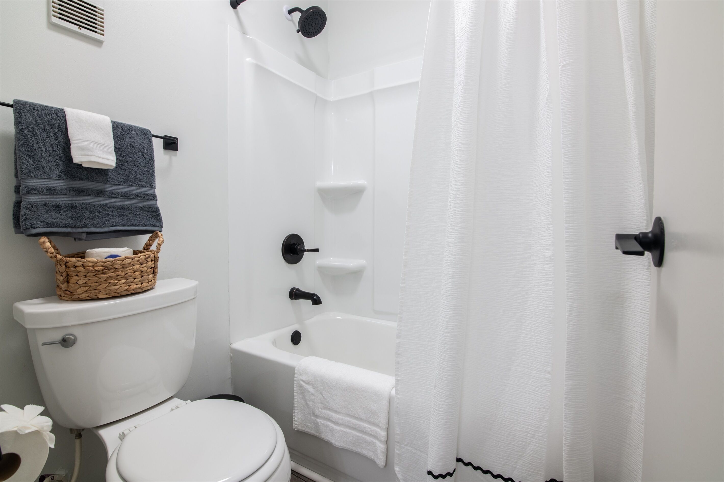Een badkamer met toilet, bad en douchegordijn.
