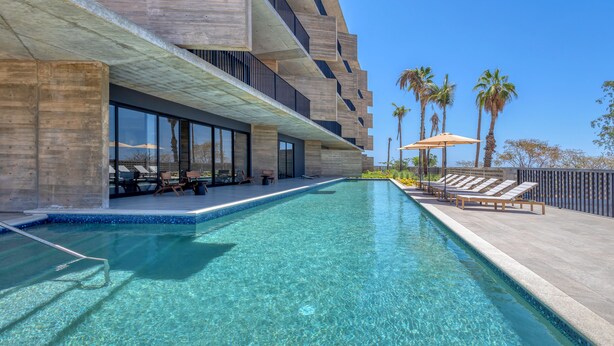 Un hôtel moderne doté d’une piscine, d’un espace extérieur aménagé et de palmiers.