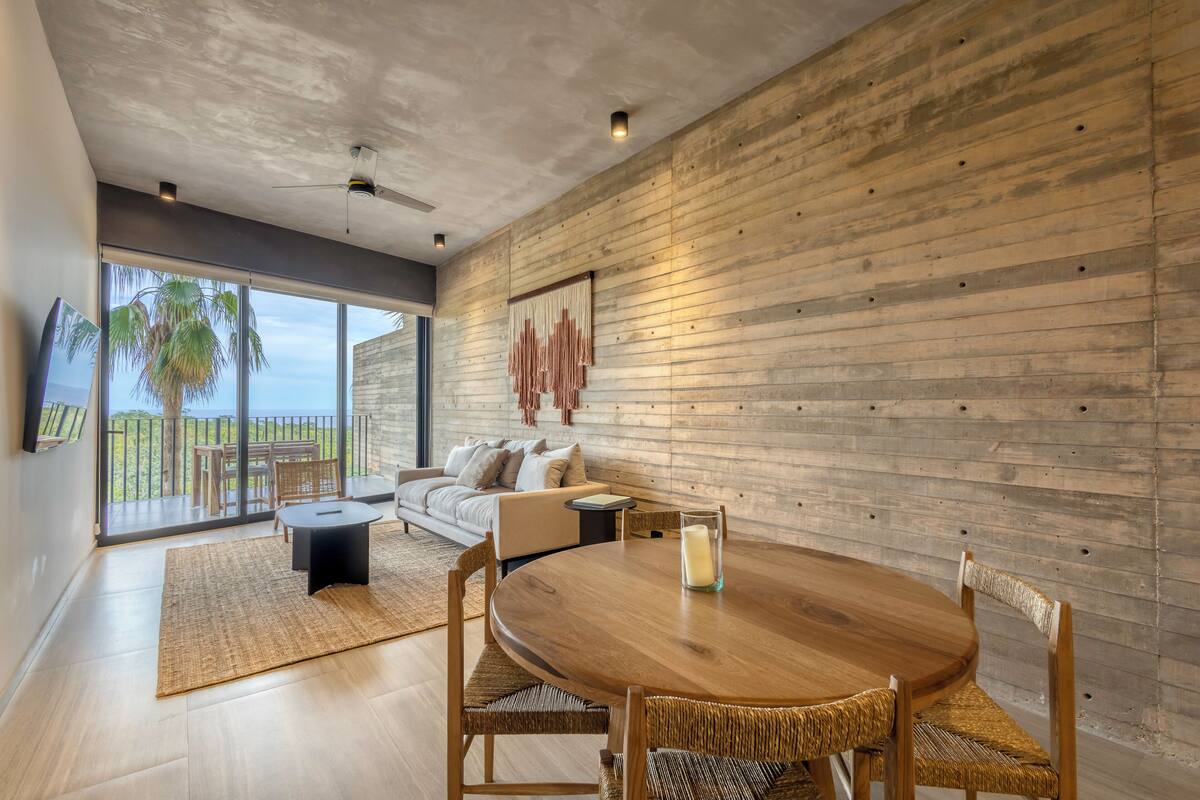 A modern living room with a wooden wall, a round wooden table, and a sofa.