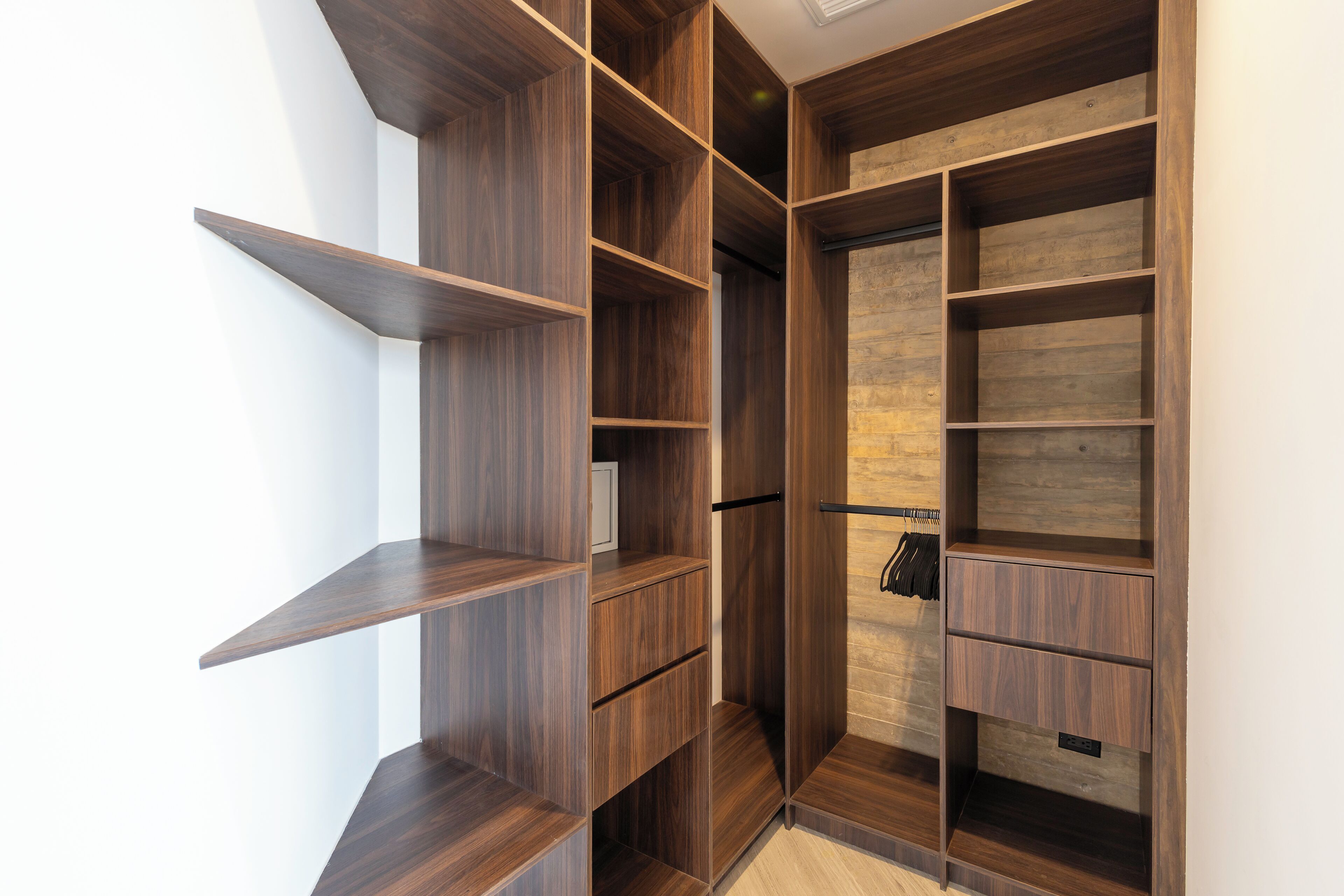 Un placard moderne doté de nombreuses étagères et tiroirs en bois, caractérisé par un design minimaliste et une palette de couleurs neutres.