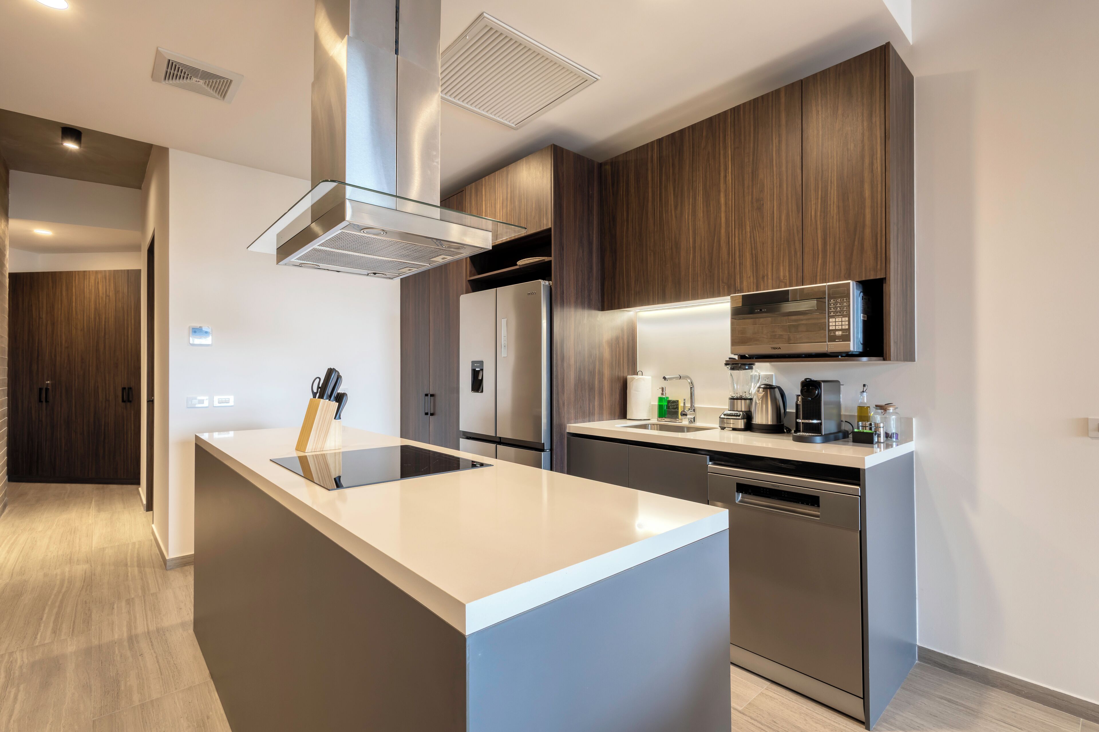 A modern kitchen with a central island, stainless steel appliances, and wooden cabinetry.
