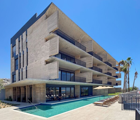 A modern building with a pool, multiple balconies, and outdoor seating. - OR Cabo Boutique Residences by Lumina (Cabo San Lucas)