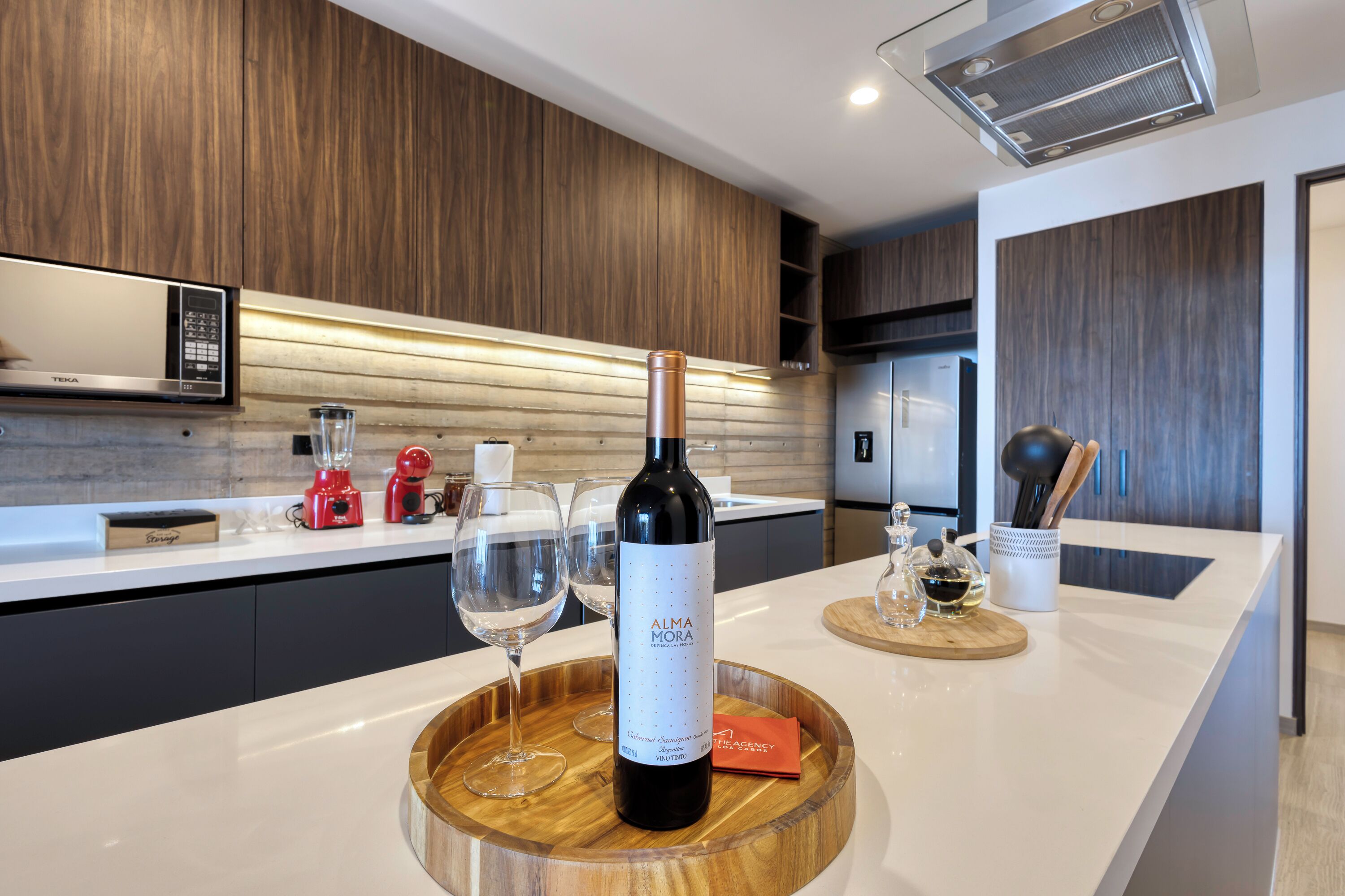 A modern kitchen with a wooden countertop, a wine bottle, and wine glasses.
