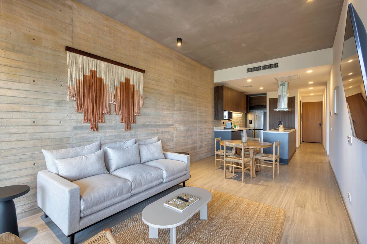 A modern living room with a sofa, a coffee table, and a dining area with chairs.