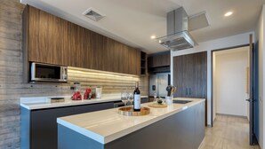Une cuisine moderne dotée d’un îlot central, d’un four à micro-ondes encastré et d’appareils électroménagers en acier inoxydable.