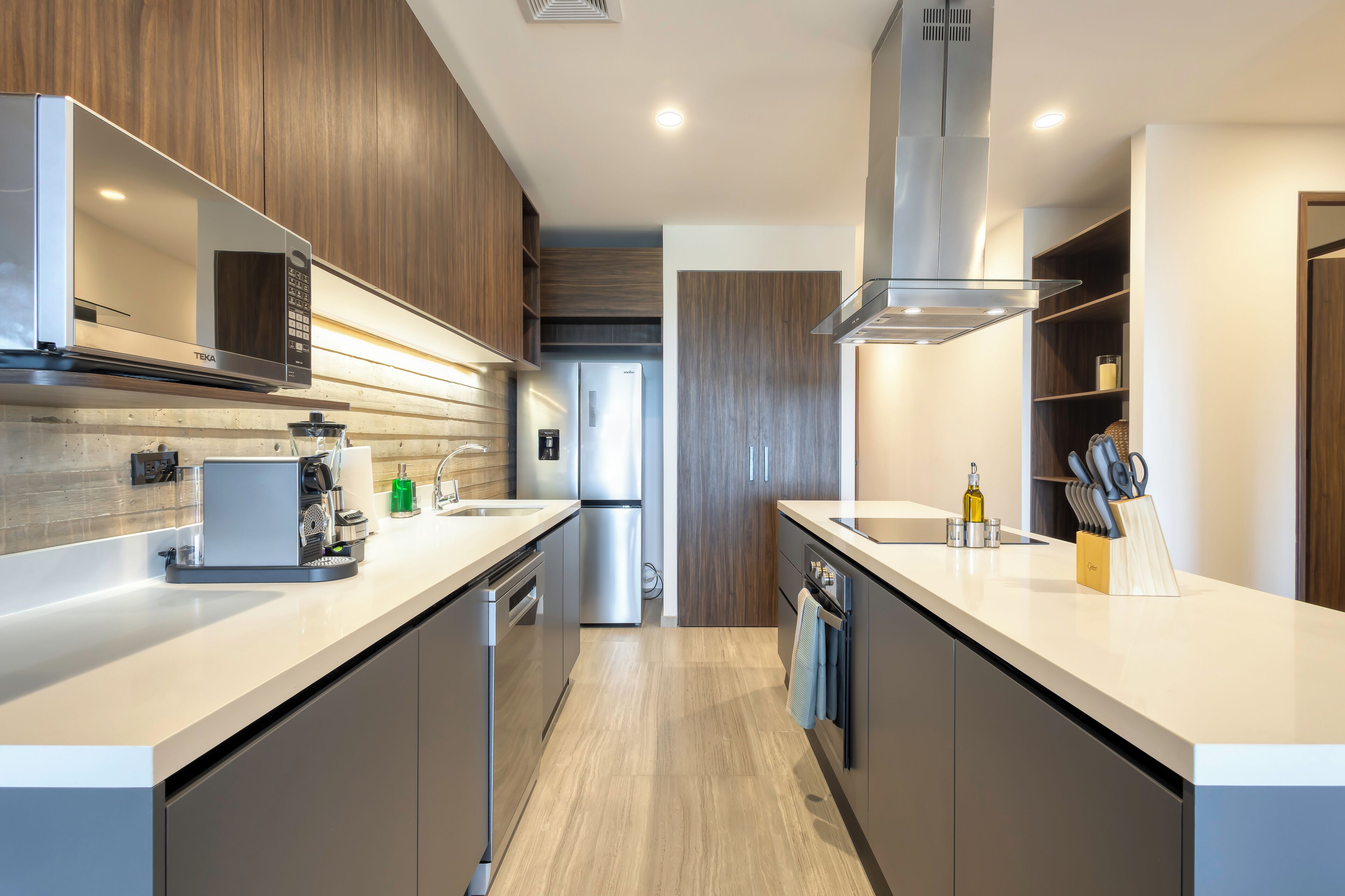 Une cuisine moderne dotée d’appareils électroménagers intégrés, de meubles en bois et d’un îlot central.
