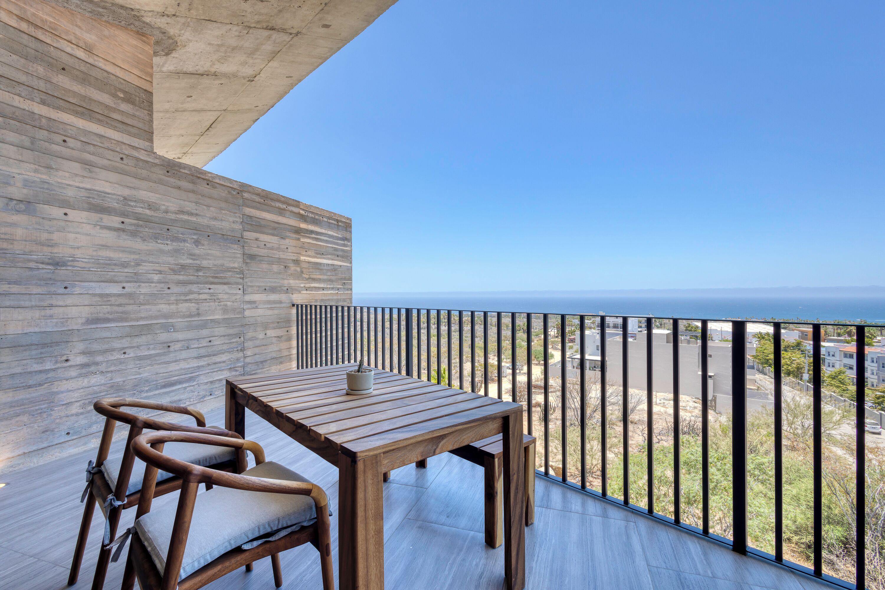 Terraza de madera con mesa y sillas, con vista al mar.