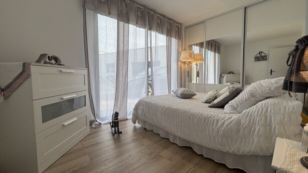 A bedroom with a bed, a dresser, a mirror, and a window with curtains. - House in Ruaudin Near Le Mans Circuit (Ruaudin)