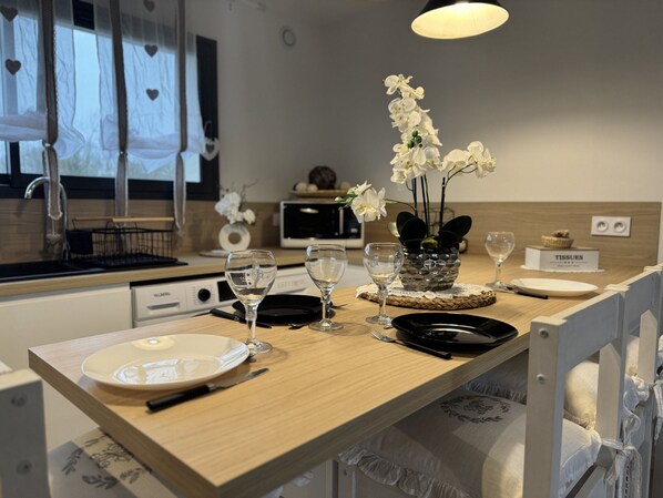Une cuisine moderne avec un plan de travail en bois, des appareils électroménagers blancs et un vase rempli de fleurs blanches.