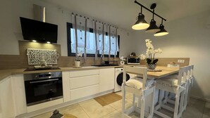 A modern kitchen with a built-in oven, microwave, and washing machine. There is a dining area with a white table and chairs. - House in Ruaudin Near Le Mans Circuit (Ruaudin)