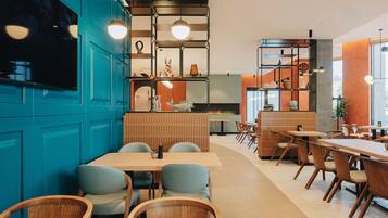 Interior moderno de restaurante con paredes azules, muebles de madera e iluminación colgante.
