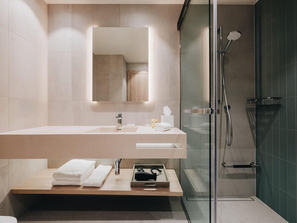 A modern bathroom with a glass-enclosed shower, a large mirror, and a wooden vanity with a sink and towel rack. - Hyatt Place Tallinn (Tallinn)