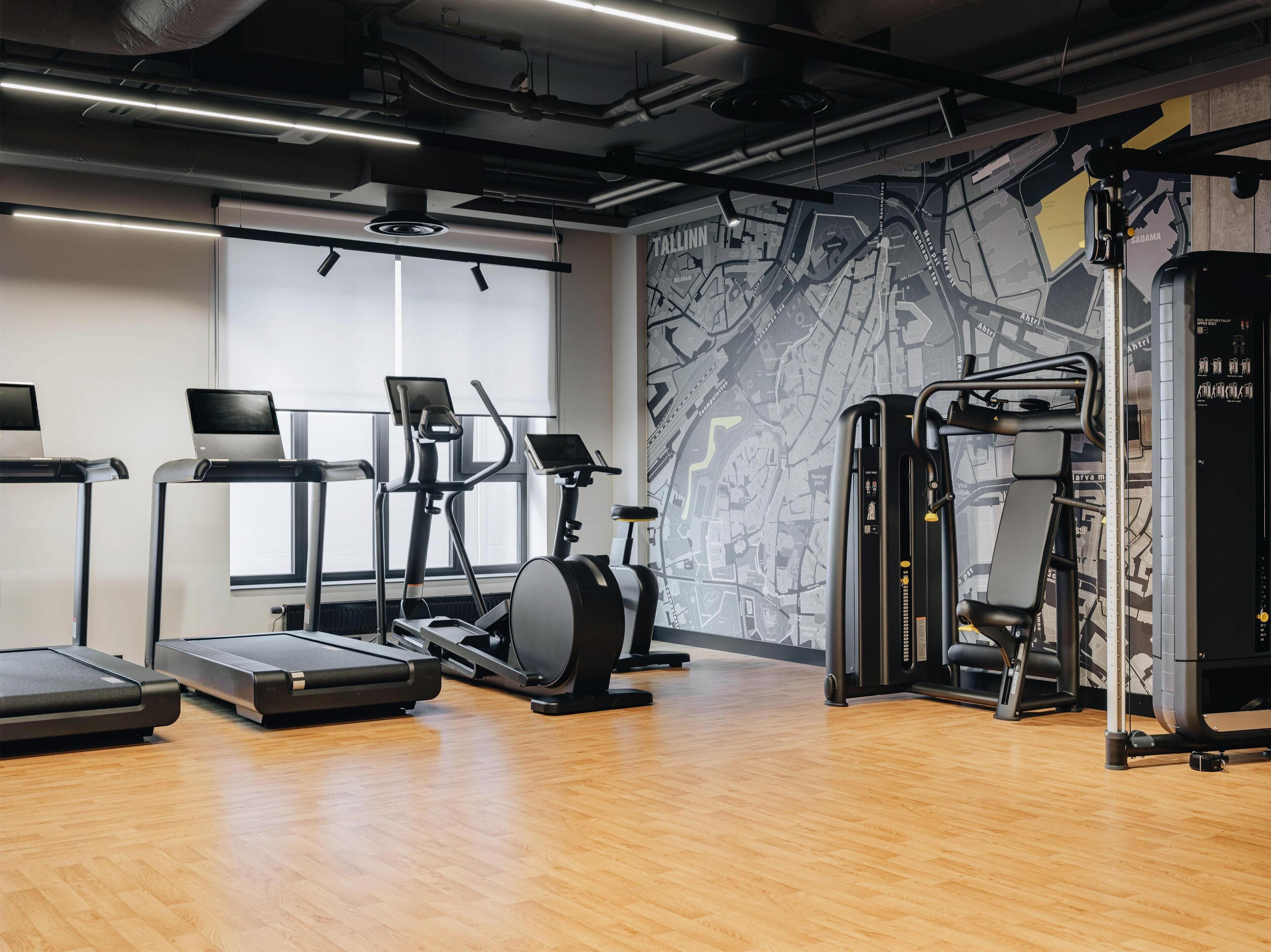 Un gimnasio con cintas de correr, elíptica y máquina de pesas.