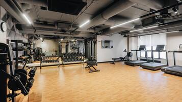 A gym with exercise equipment, treadmills, and a wooden floor.