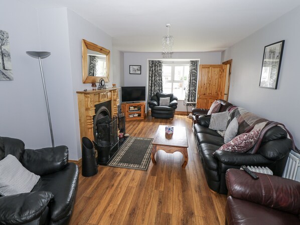 A living room with a fireplace, leather sofas, a coffee table, and a television. - 22 White Maples (Bundoran)