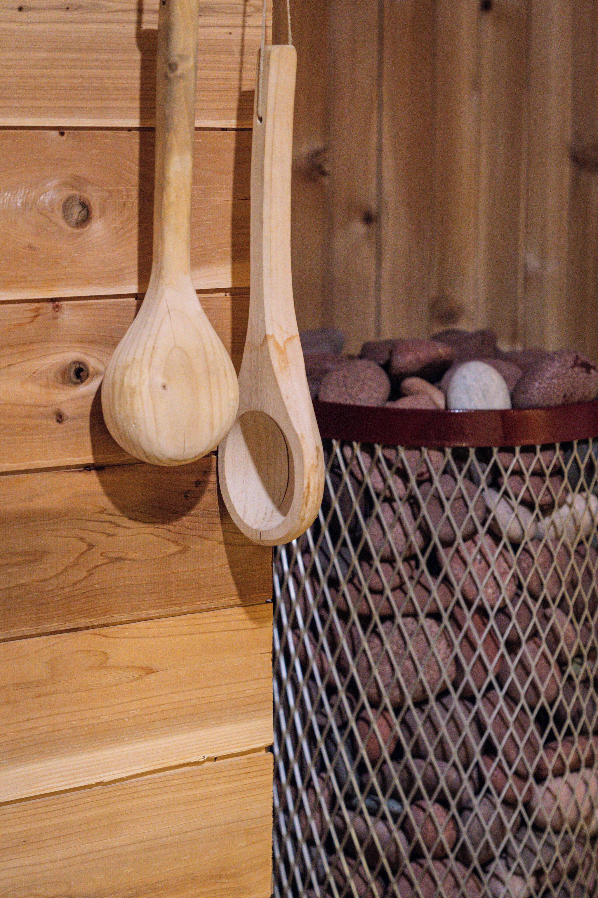 Ein Holzlöffel hängt an einer Wand, und ein Netzbehälter ist mit Steinen gefüllt.