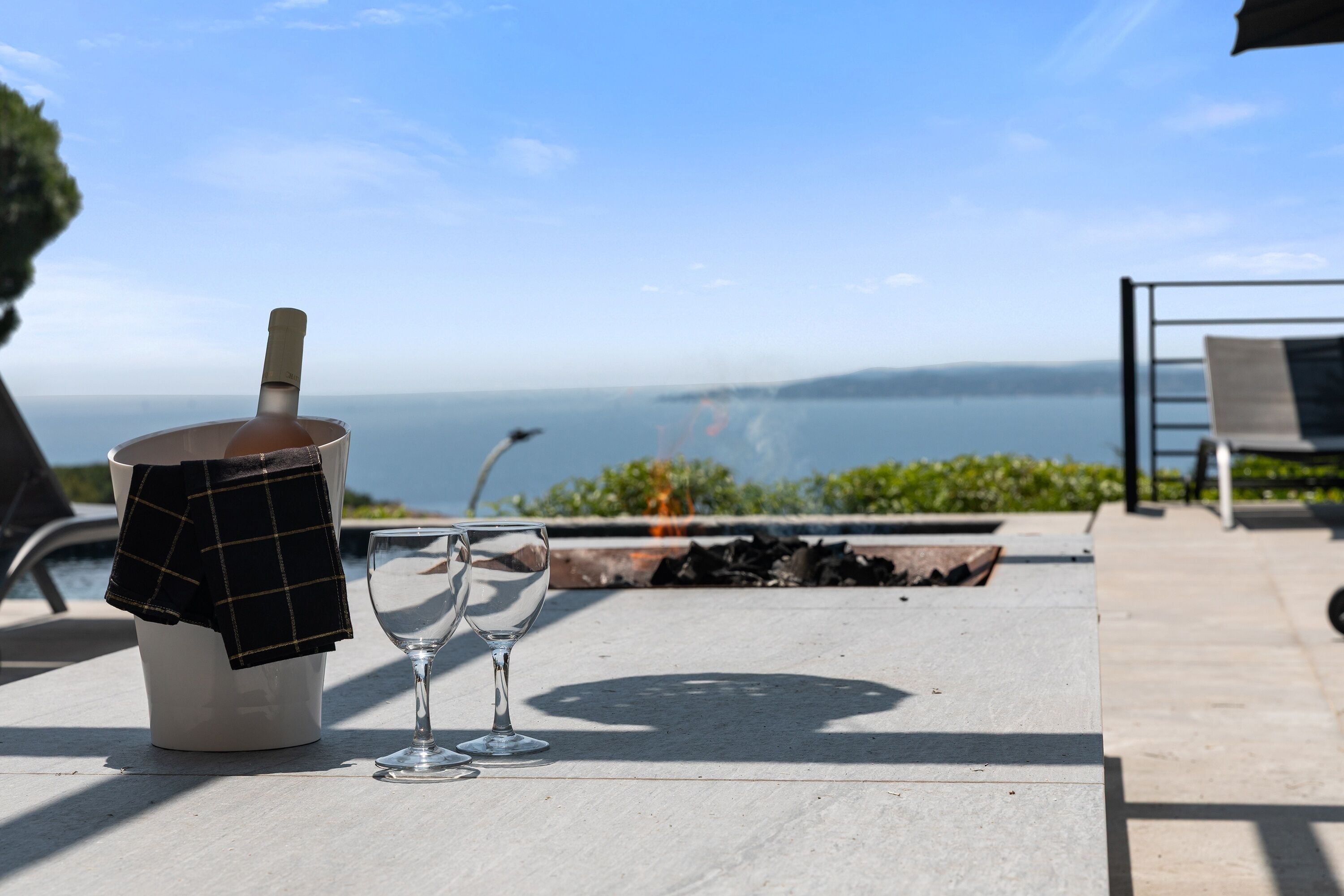 A table with a glass and a bottle, overlooking a scenic view.