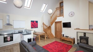 Un espace de vie moderne comprenant une cuisine, un coin repas et un escalier menant à un niveau supérieur.