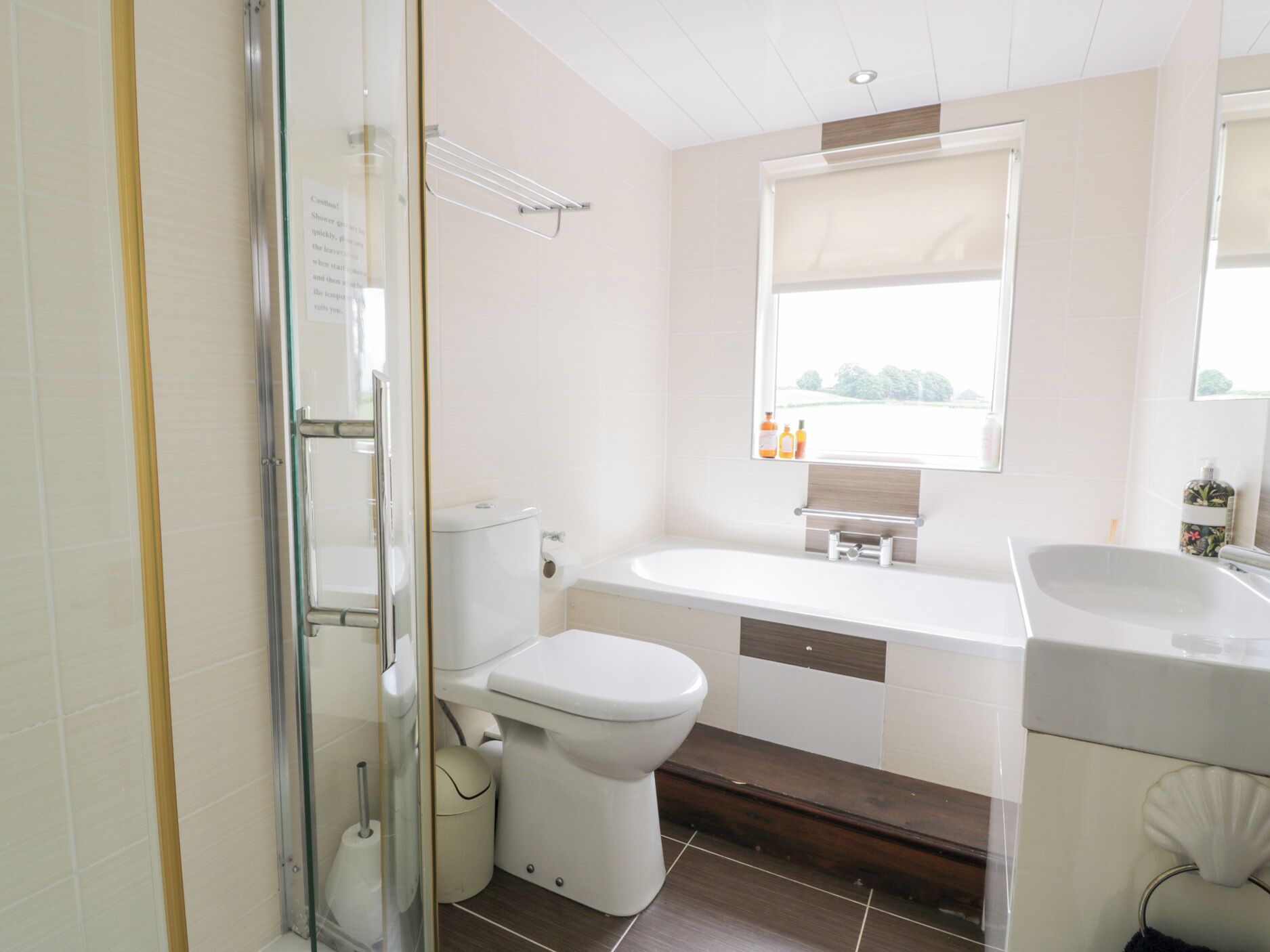 Un baño moderno con cabina de ducha de vidrio, inodoro, bañera y tocador con espejo.