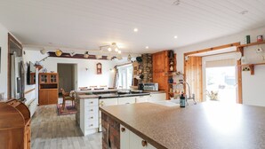 A kitchen with a large island, wooden cabinets, and a stone accent wall. - Marshill Farm House (Lanark)