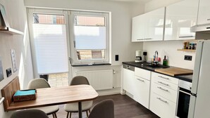 Una cocina moderna con armarios blancos, una mesa de comedor de madera y dos sillas.