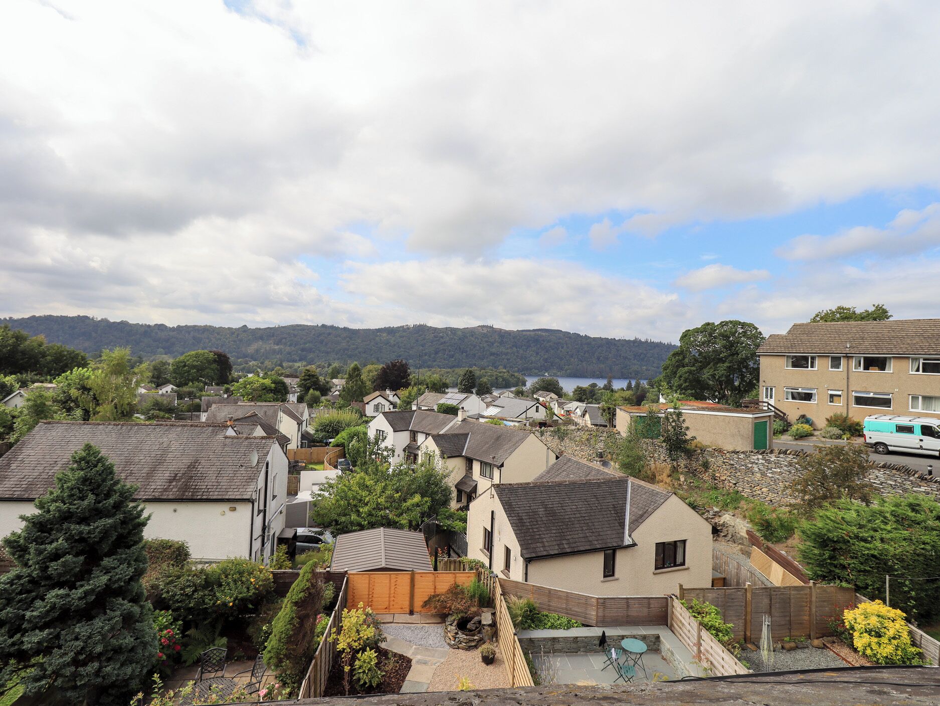 A residential area with houses, a small garden, and a distant lake.